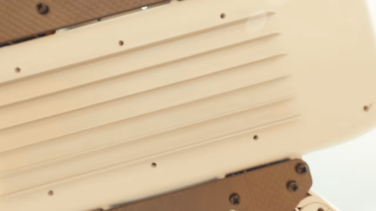 Close-up of a beige drone base with ventilation slats and several screws on its surface.