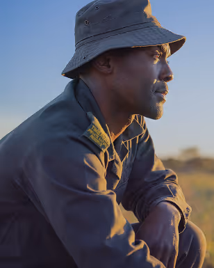 Man in uniform and hat looking thoughtfully into the distance during sunset.
